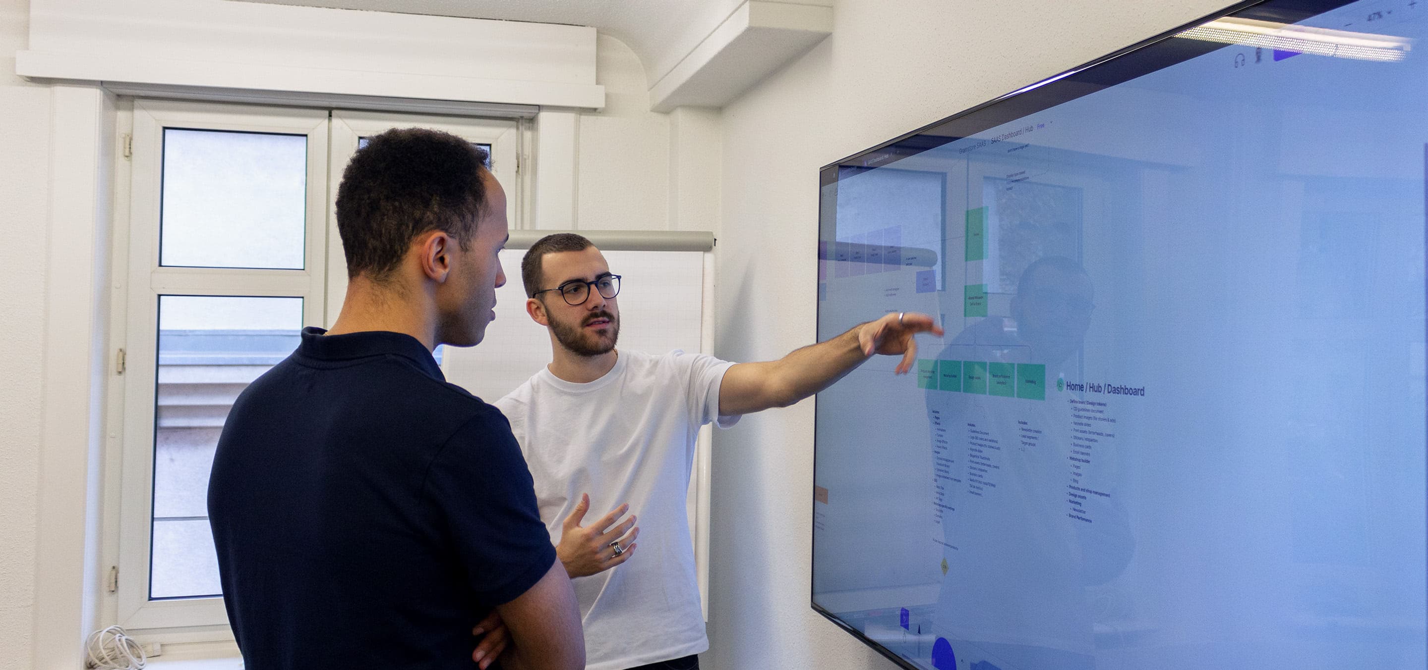 Two people discussing next to a conference screen